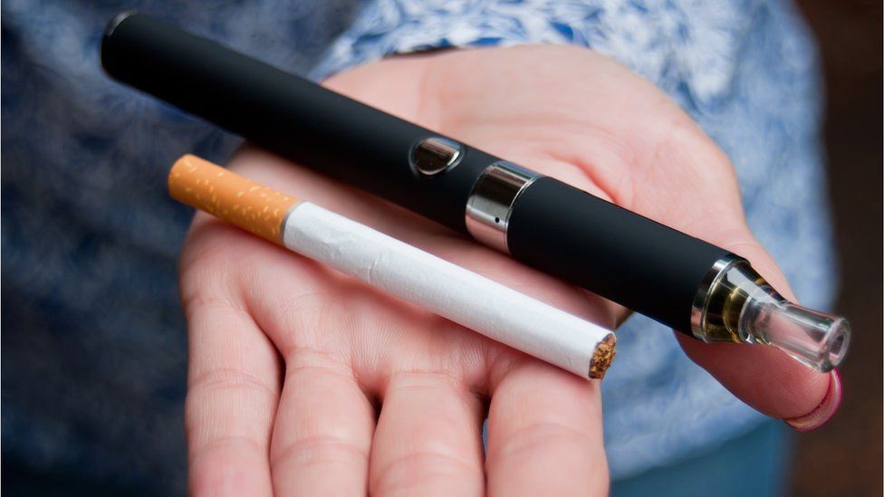 An e-cigarette and a normal cigarette in a woman's hand