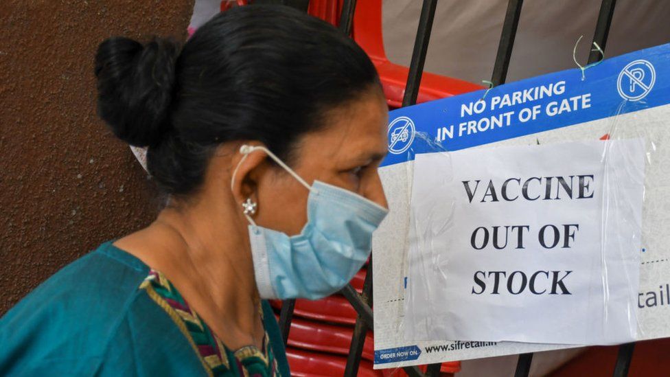 A woman wearing a facemask as a precaution against the spread of covid-19 seen reading a poster saying 'vaccine out of stock' outside a vaccination center in Mumbai.