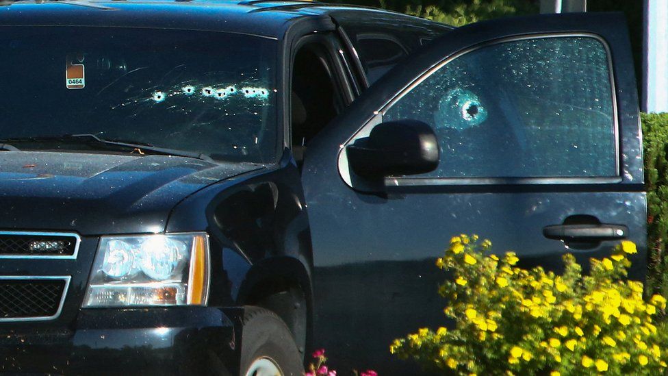 Image shows a bullet-riddled vehicle near the shooting site