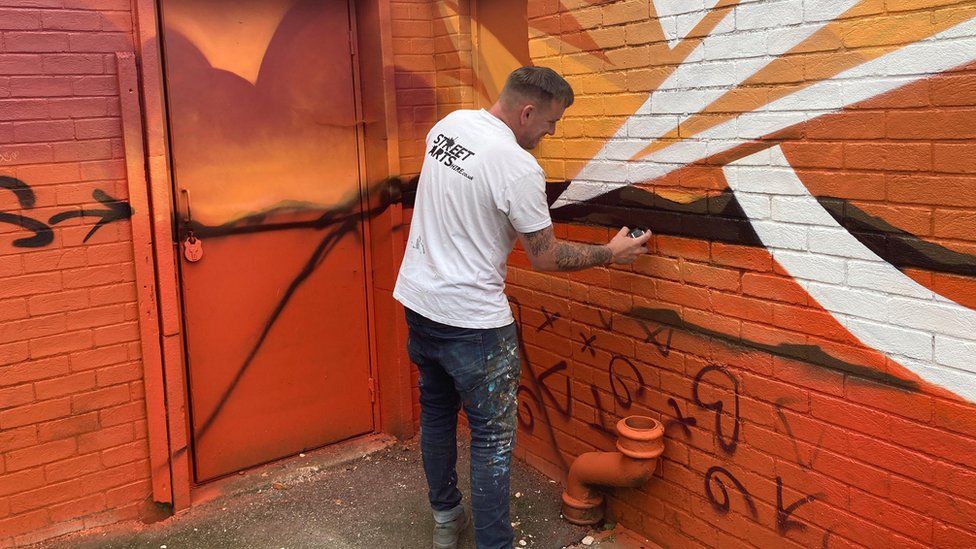 Nathan painting an old toilet block