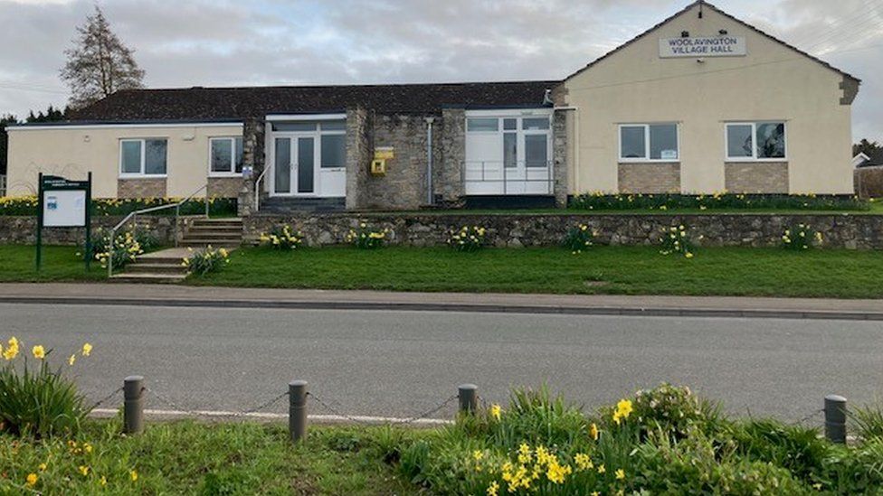 A village hall by a road with daffodils outside