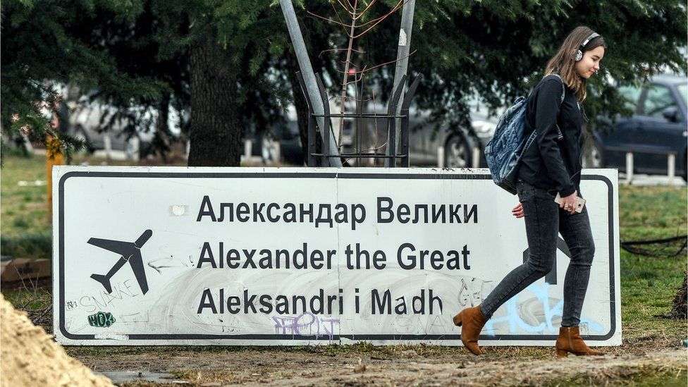 A woman walks past the removed sign for the airport Alexander the Great in Skopje on February 19, 2018