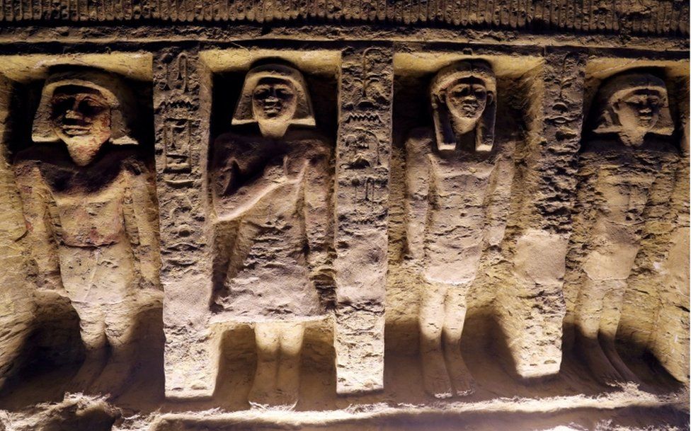 Four statues of people carved into the wall of the tomb