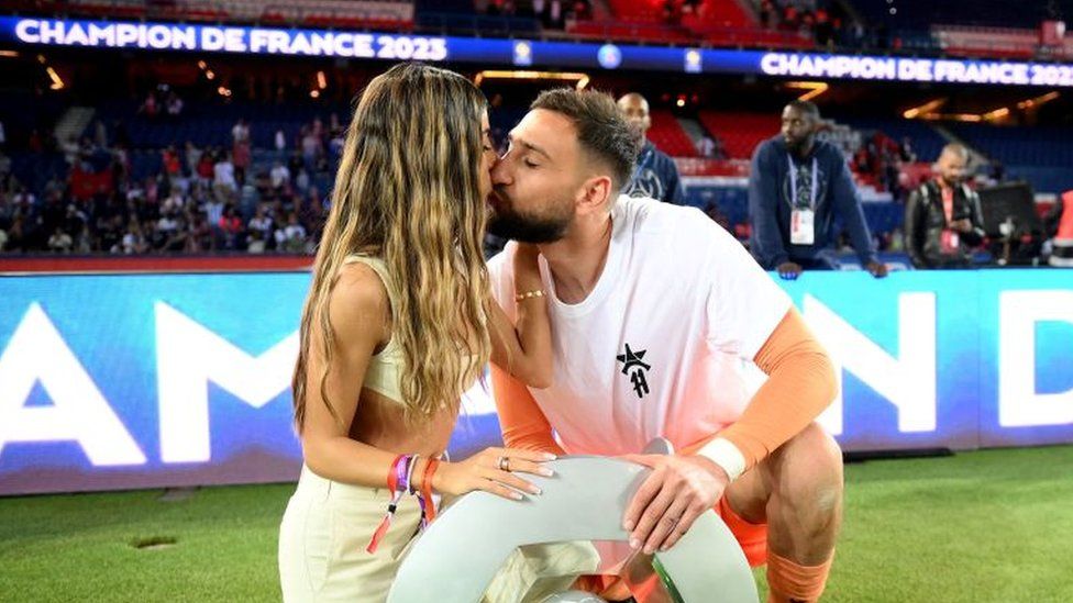 Paris Saint-Germain's Italian goalkeeper Gianluigi Donnarumma kisses his partneras they airs  with the trophy during the 2022-2023 Ligue 1 title  trophy ceremony