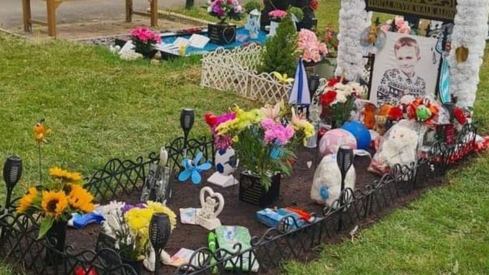 Harry-Lee's grave with metal fencing around it and bunches of flowers