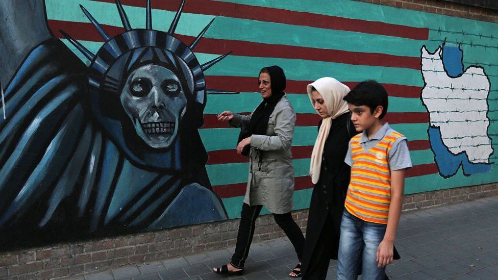 Iranians walk past anti-US graffiti in Tehran (file photo)
