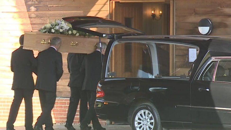 The coffin being carried into the crematorium