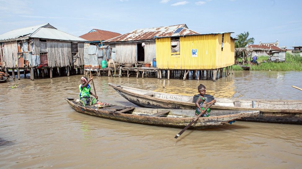 Children are seen riding a rowboat at Lake Nokoue in Ganvie Village of Cotonou, Benin.