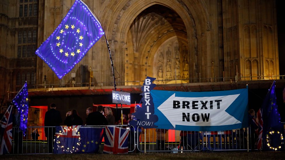 Anti-Brexit protesters with signs and EU flags lit up with fairy lights stand next to pro-Brexit banners outside the Houses of Parliament in London on September 9, 2019 as MPs debate