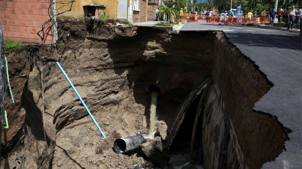 Workers stand by a collapsed street after a flood caused by heavy rain, in the aftermath of tropical storm Bonnie, in San Salvador, El Salvador July 3, 2022