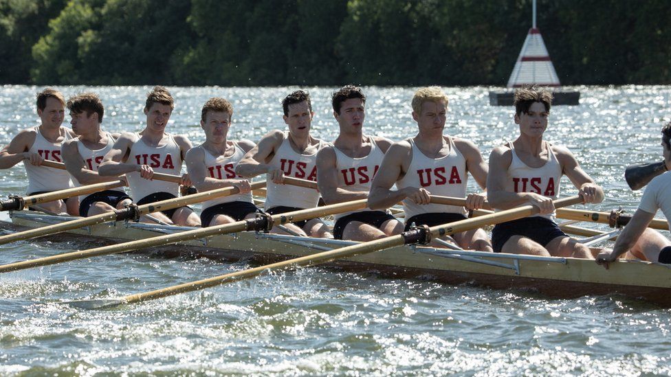 A still from the film showing the cast rowing