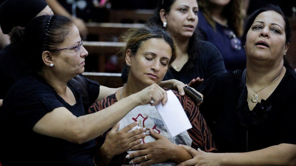 The wife of Coptic priest Abdul Masih Bakhit holds part of his vestments at a funeral service at the Church of the Blessed Virgin Mary in Giza, Egypt (14 August 2022)