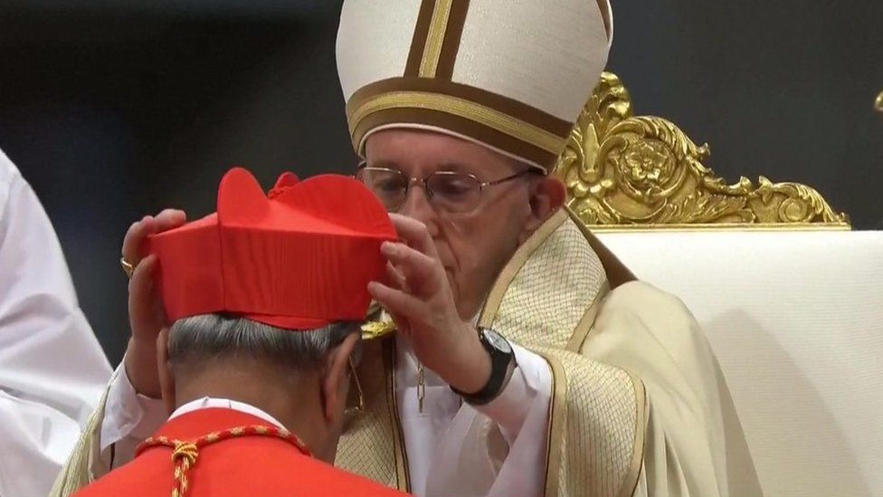 Pope putting hat on cardinal