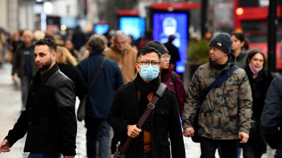A man wearing a protective face mask walks on Oxford Street
