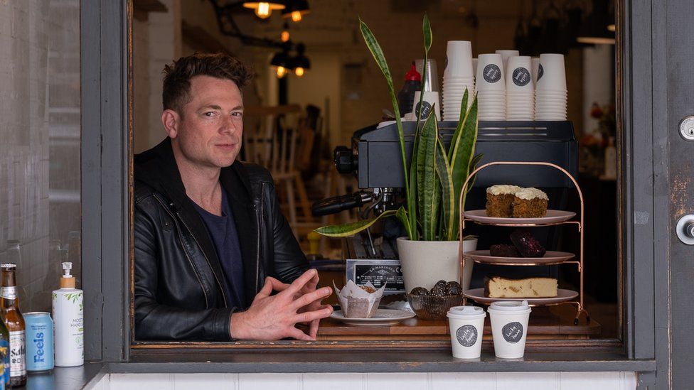 Matt Lanigan sits in his takeaway shop window next to a coffee machine