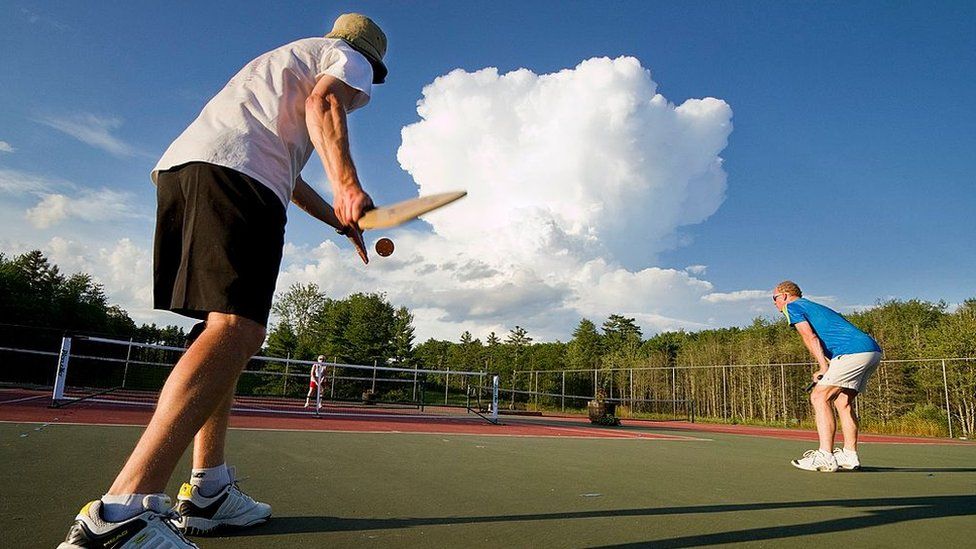 A pickleball player gets ready to serve