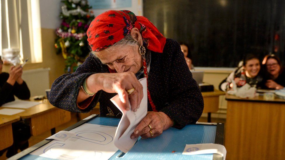 A woman wearing a red head scarf casts her vote in Sintesti, south of Bucharest, Romania
