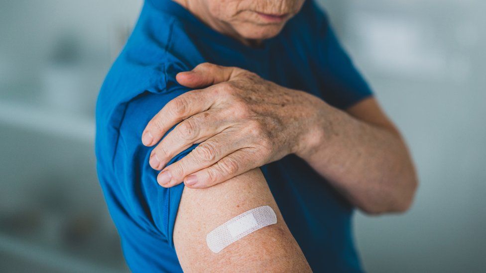 Older patient with plaster on arm after vaccine jab