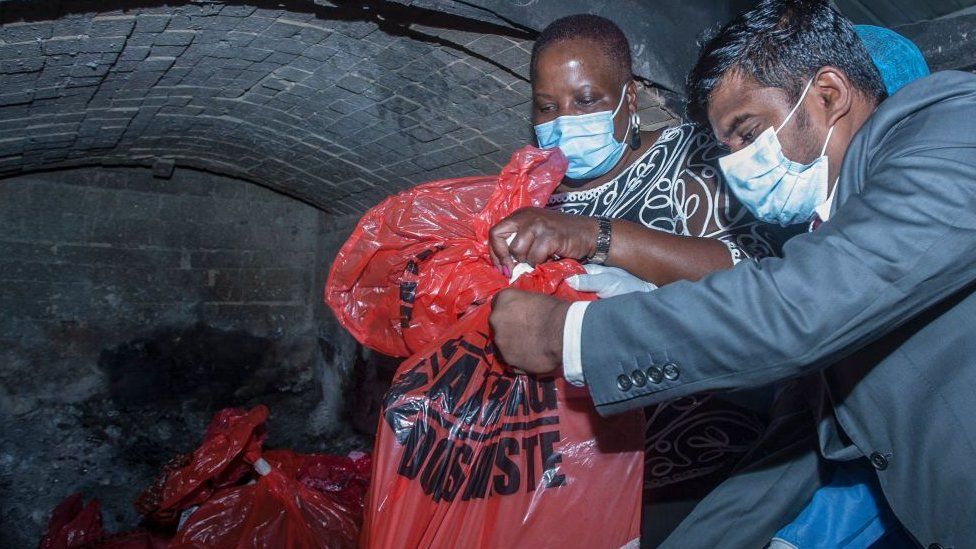 Malawi's Health Minister Khumbize Kandodo Chiponda (C) puts packs of expired Covid-19 Astra Zeneca in a pharmaceutical incinerator to destroy them at Kamuzu Central Hospital in Lilongwe on May 19, 2021.