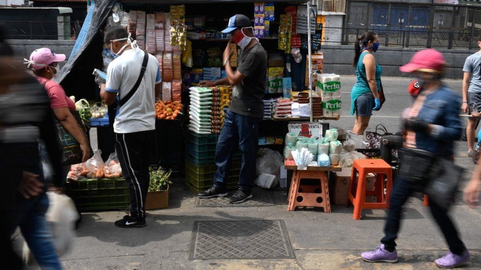 People wear face masks in a market as a preventive measure against the spread of the new coronavirus, COVID-19, at the Petare neighborhood in Caracas, on April 2, 2020