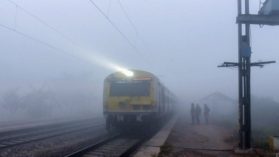 GHAZIABAD, INDIA - DECEMBER 27: Commuters out a cold and Dense Fog morning amid rising air pollution levels at Adhyatmik Nagar railway track train on December 27, 2023 in Ghaziabad, India. Dense fog causes low visibility in Delhi-NCR, impacting flights and trains. Delhi airport experiences flight delays. India Meteorological Department issues orange alert for today and yellow alert for Thursday due to dense fog. Weather forecast predicts foggy conditions for the next three days. The air quality remains very poor with a potential for it to become severe. Temperatures range from 7 to 24 degrees Celsius. (Photo by Sakib Ali/Hindustan Times via Getty Images)
