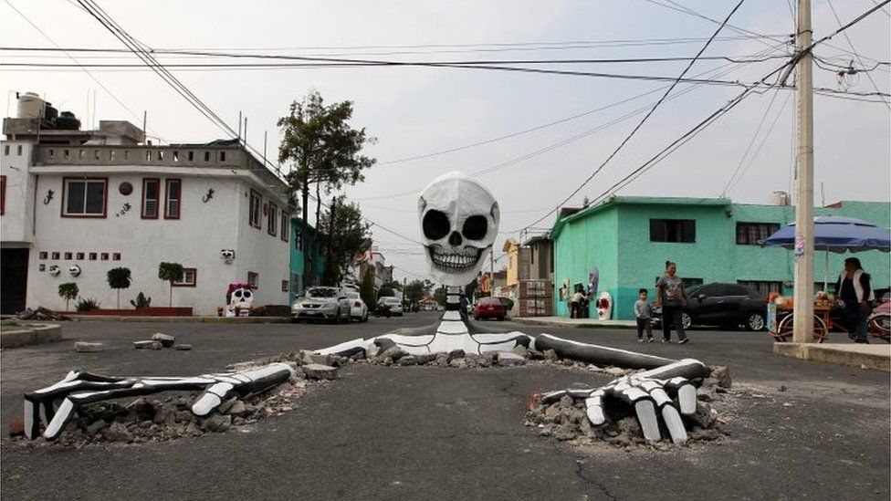 A cardboard skeleton emerges from a street in Mexico City