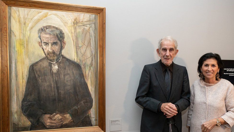 Victor de Waal (second right) stands beside a painting of himself as Dean of Canterbury Cathedral