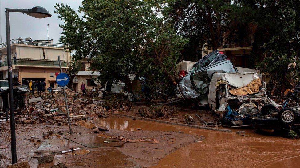 Car wreckages are piled up in a flooded street of Mandra, northwest of Athens