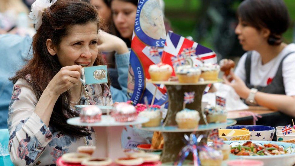 A woman looks on as people celebrate Britain's King Charles' coronation with the Big Lunch at Regent's Park, in London