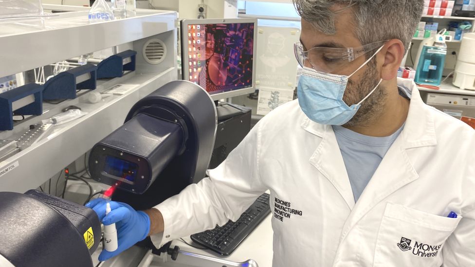 Ученый держит бутылку назального спрея с гепарином в лаборатории Мельбурна