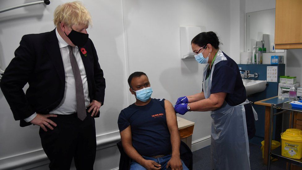 Prime Minister Boris Johnson watching as a patient receives a booster jab