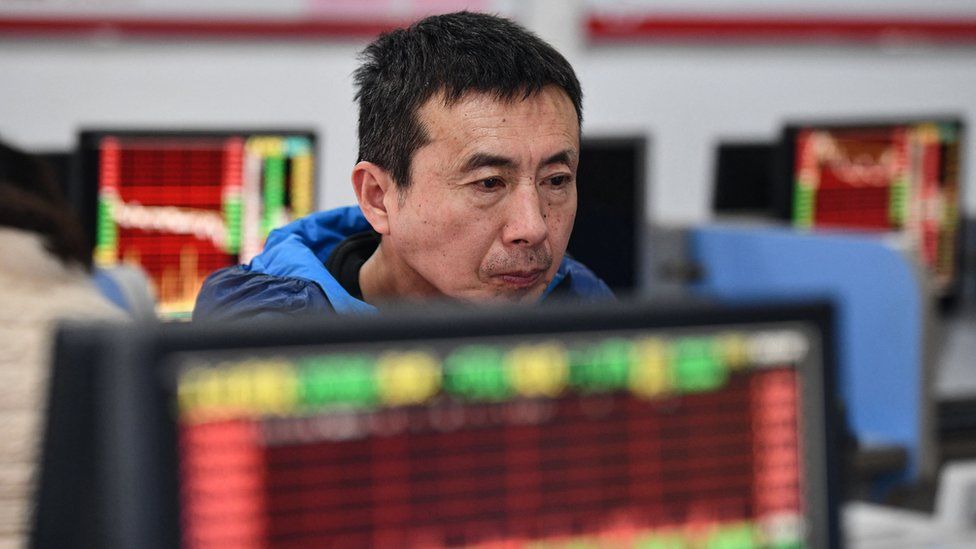 A Chinese investor looks at screens showing stock market movements.