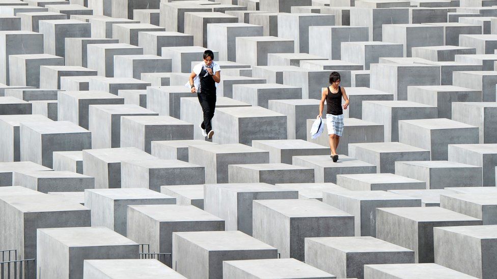 his file photo taken on August 6, 2010 shows two tourists jumping over the concrete steles of Holocaust Memorial in Berlin.