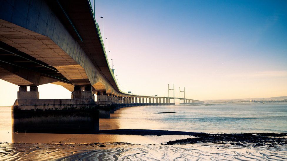 The Severn Bridge seen from Severn Beach with mudflats in the foreground and the bridge stretching off into the distance