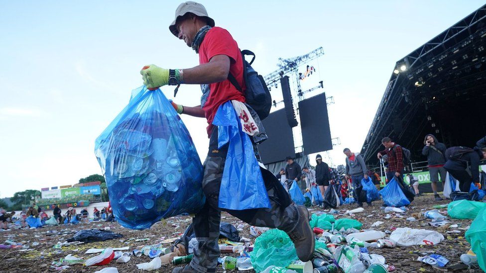 A man carries a bin bag in front of the Pyramid Stage at Glastonbury