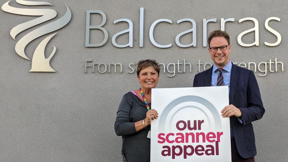 A man and a woman holding a scanner appeal sign