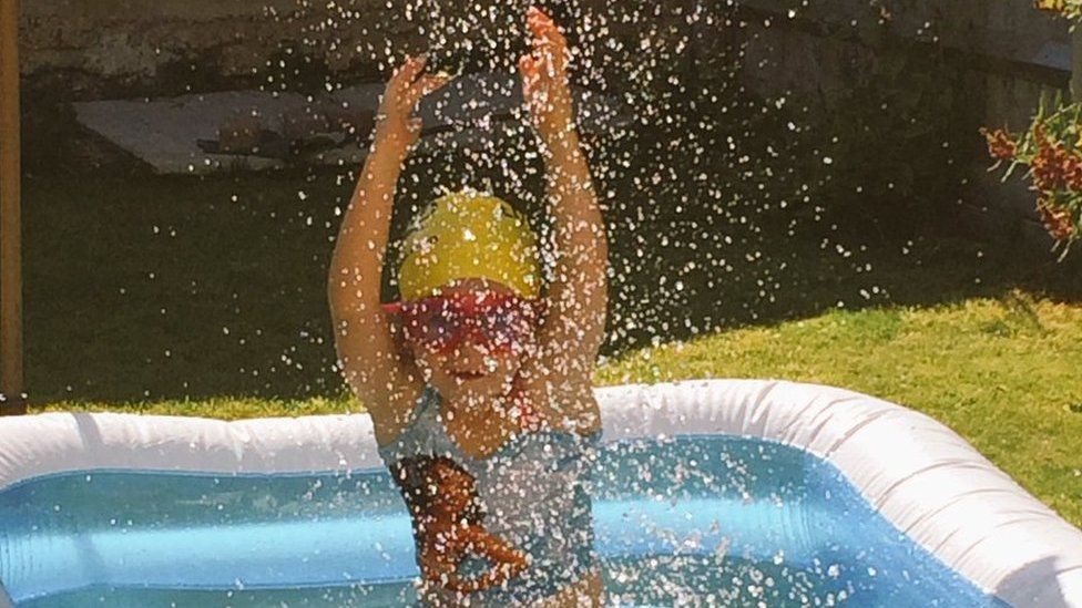 Young girl splasshing in a paddling pool