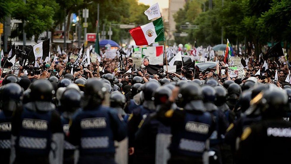 Protestors face a line of riot police in Mexico City