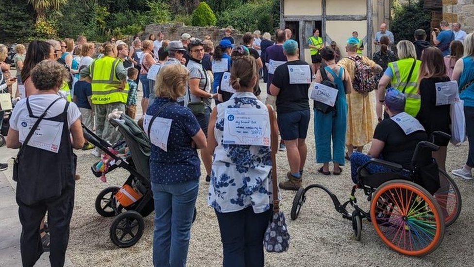 A large group of people standing with signs on their back