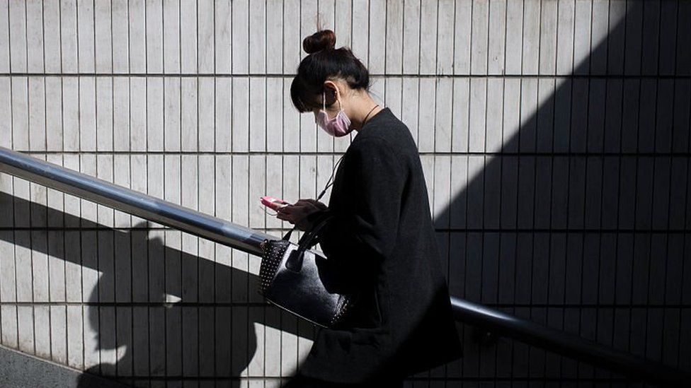 A woman walks as she reads her text on her phone in Beijing, on 23 March 2016.