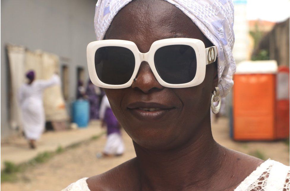 Woman wearing chunky white-rimmed sunglasses and a white headscarf.