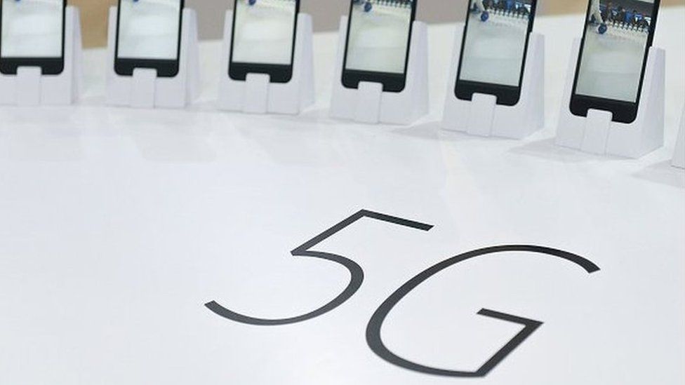Smartphones positioned next to a 5G sign