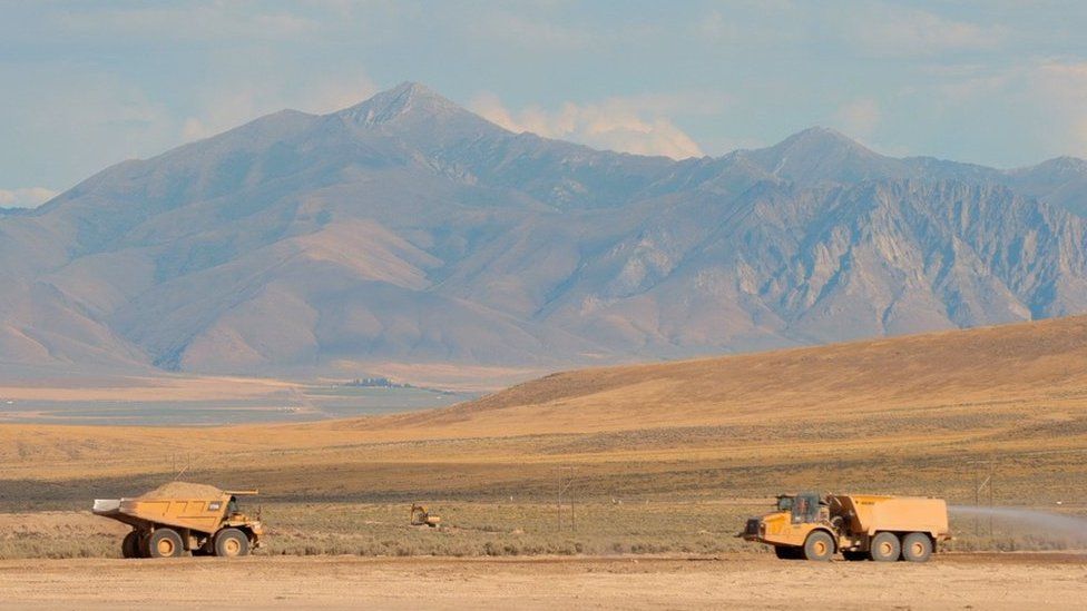 Two mining trucks against the backdrop of the mountainous vistas of the Nevada desert in the US
