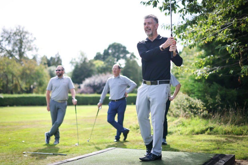 three men watch a player take his shot