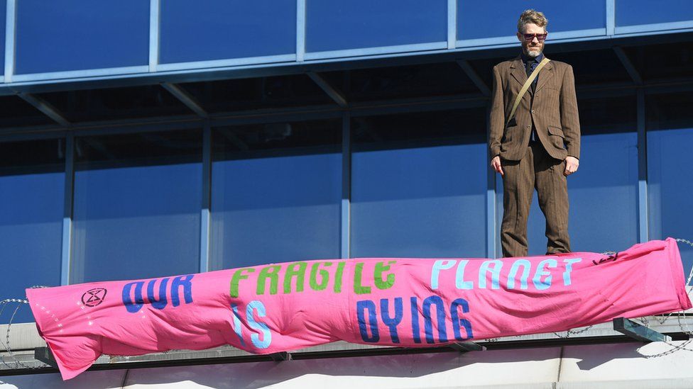 A protester stands on the roof of the terminal building at London City Airport