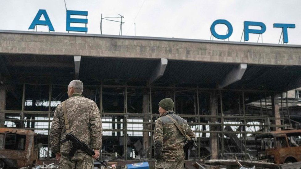 Ukrainian soldiers stand in front of a destroyed building of the International Airport of Kherson in the village of Chornobaivka, outskirts of Kherson, on November 20, 2022