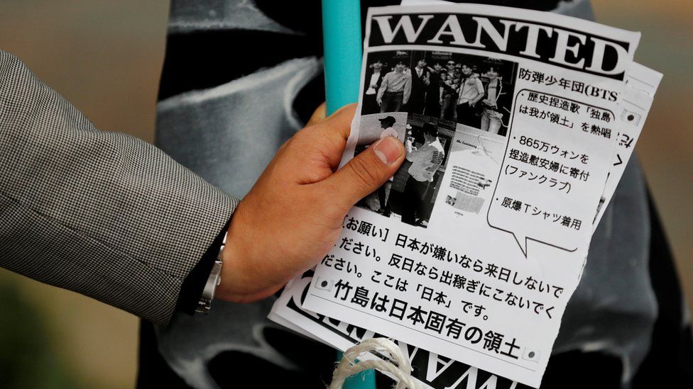 A man holds leaflets denouncing South Korean boy band BTS outside Tokyo Dome