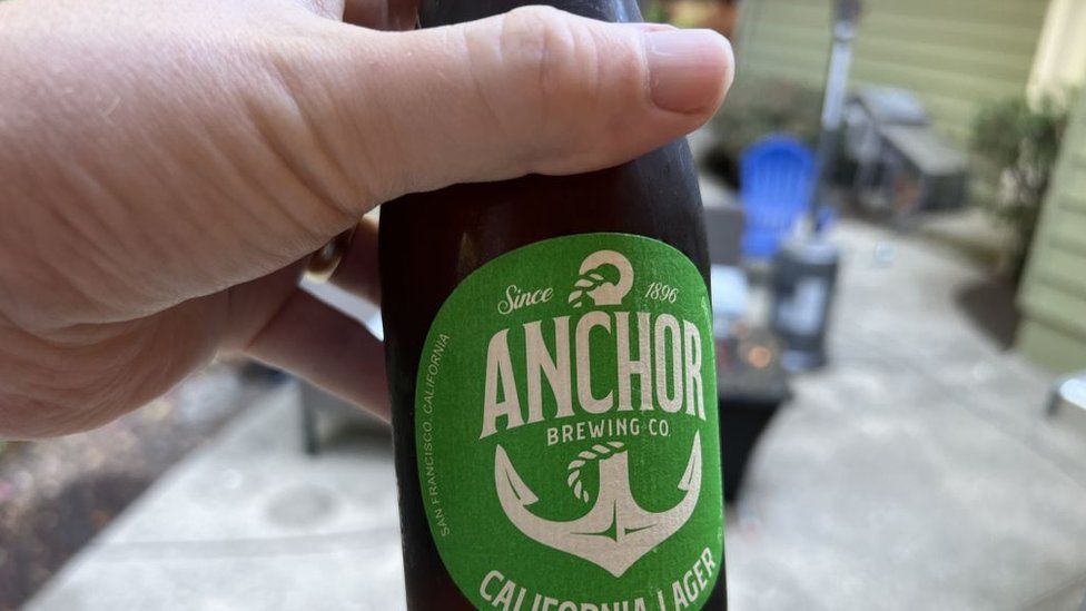 a person holds an Anchor Brewing bottle