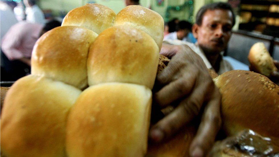 In this photograph, an Indian baker arranges a display of fresh bread in Mumbai