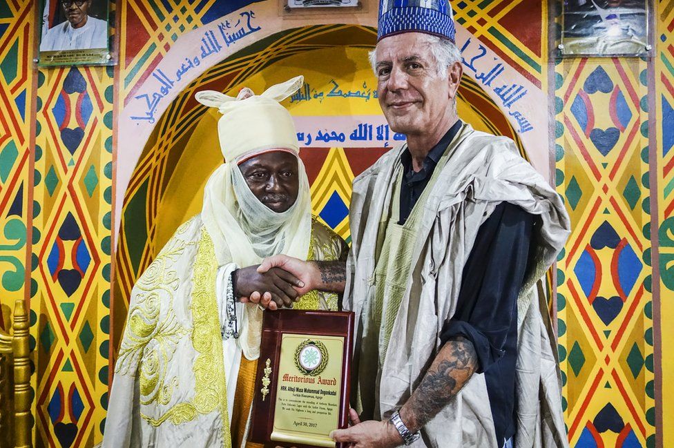 Bourdain accepts an award during a visit to Nigeria.
